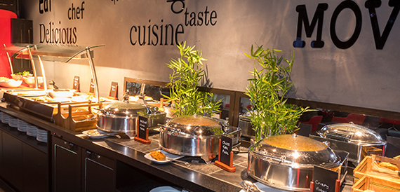 Buffet food counter with chafing dishes and potted plants