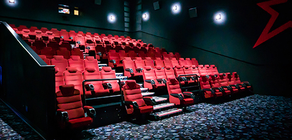 Cinema auditorium in near darkness with red seats and spotlighting