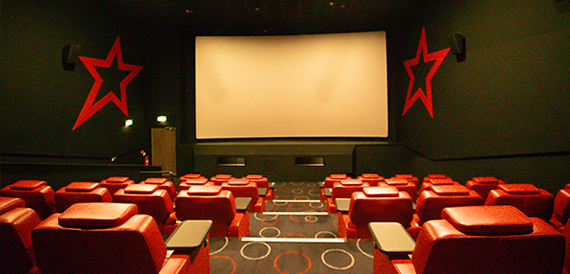 Empty auditorium with red seats, tray tables and star wall decorations