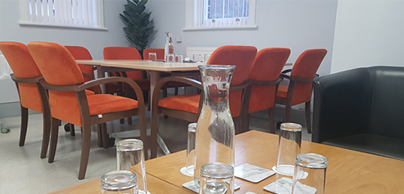 Orange chairs around a table with a water carafe and glasses