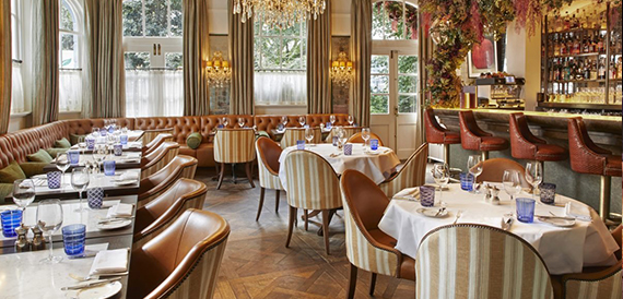 Restaurant with striped chairs, a leather booth and floral archway near the bar