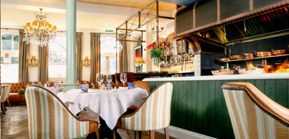 Restaurant seating with striped chairs beside a green-panelled bar
