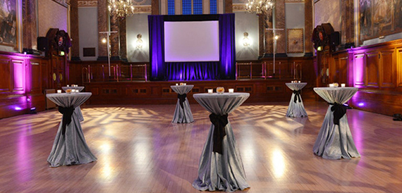 Grand hall dressed for an evening event with purple uplighting and cocktail tables