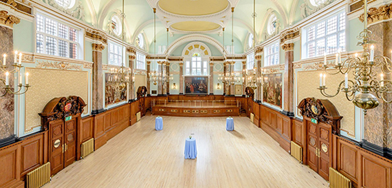 Empty grand hall with an ornate ceiling, chandeliers and a polished wood floor
