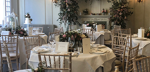 Table set with a candelabra and place card before a flower-decked fireplace