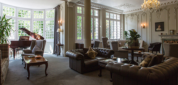 Drawing room with a grand piano, leather chesterfield sofas and a chandelier