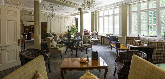 Drawing room lounge with tartan sofas, armchairs and ornate plasterwork ceiling