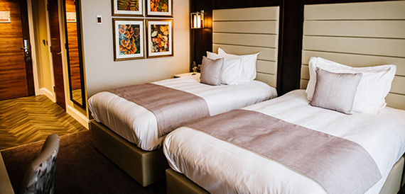 Twin bedroom with two beds dressed in pink and white linen