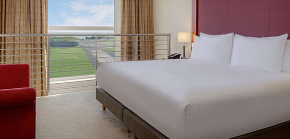 Hotel bedroom with a made bed and a window overlooking a golf course.
