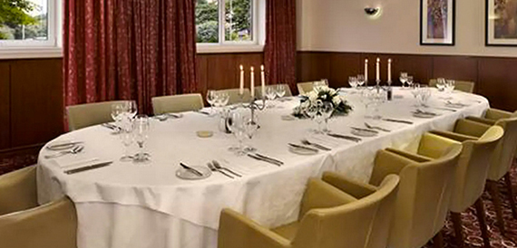 Private dining table dressed in white linen with candles and formal place settings.