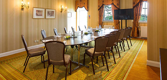 U-shaped meeting room with framed pictures and a wall-mounted screen
