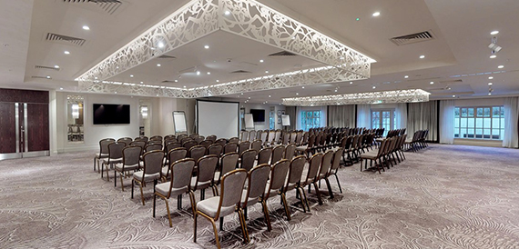 Conference room set theatre-style beneath an ornate ceiling feature