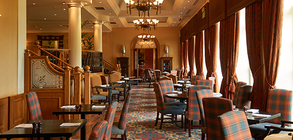 Restaurant with tartan upholstered chairs and a wooden staircase