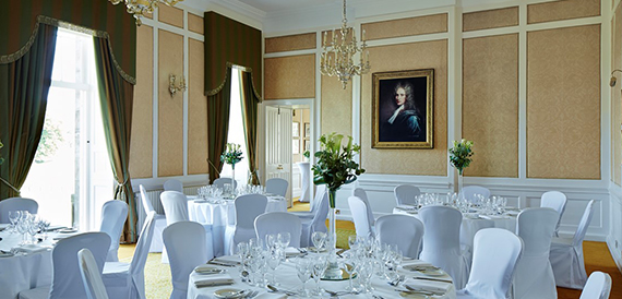 Banqueting room with round tables set beneath a portrait painting
