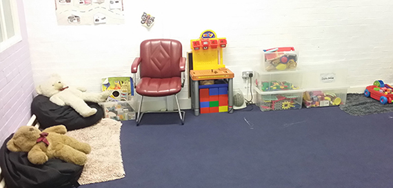 Small playroom with a red armchair, toy box and children's activity table.