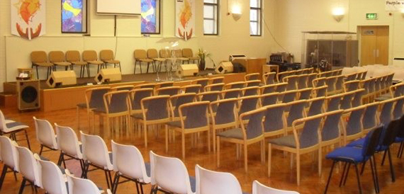 Auditorium with rows of chairs facing a stage decorated with flame-themed banners.