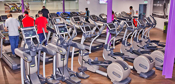 Gym floor with rows of treadmills and cross trainers in use.