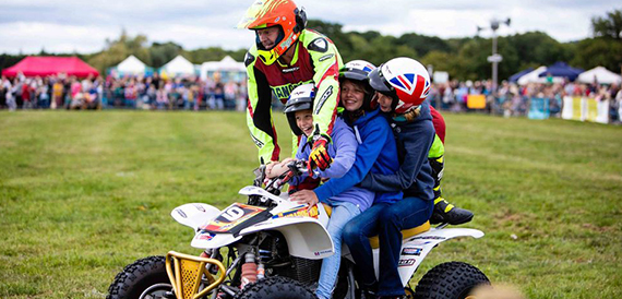 Family riding a quad bike together on the showground field.