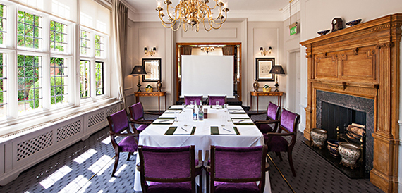 Private dining room with blue panelled walls, purple velvet chairs and a fireplace.