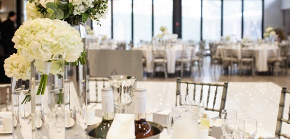 Table centrepiece with white hydrangeas overlooking a lit dance floor.