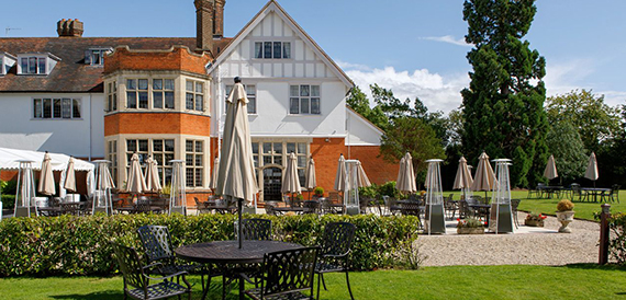 Hotel exterior with a terrace of tables, umbrellas and patio heaters.