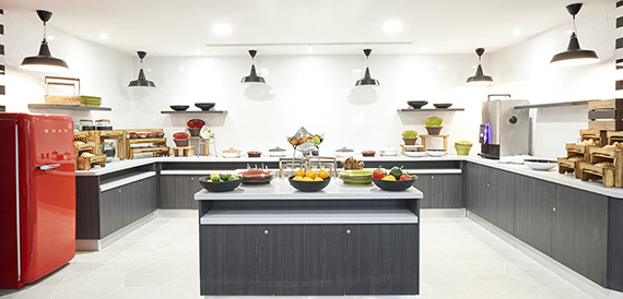 Breakfast buffet counter with a red retro fridge, fresh fruit and pastry displays