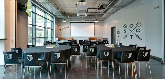 Boardroom-style oval table setup with crested chairs and a projector screen