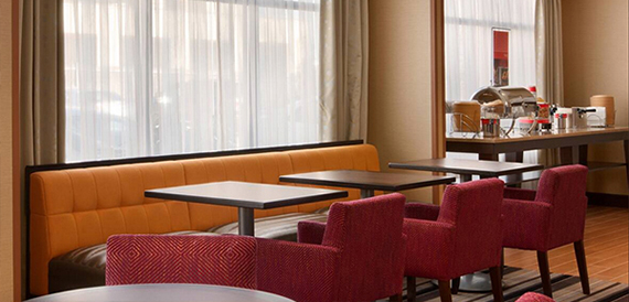 Breakfast lounge with an orange banquette seat and red dining chairs.