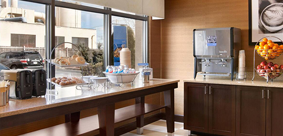 Breakfast buffet counter with pastries, fresh fruit and a drinks dispenser.