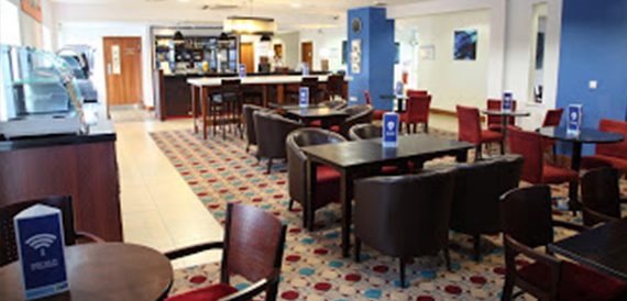 Bar area with red armchairs, a patterned carpet and a service counter.
