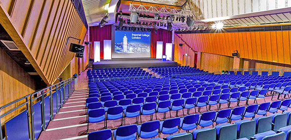 Wide view of a lecture theatre with rows of blue tiered seats
