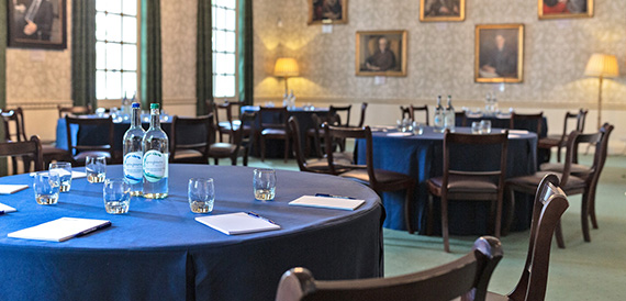 Round table dressed in blue linen beneath framed portraits