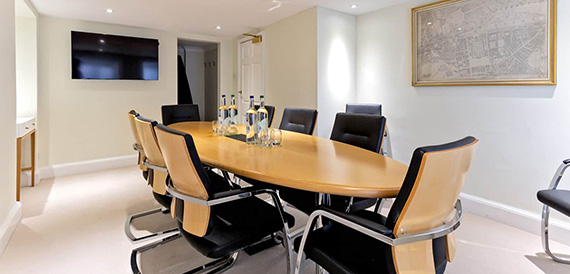 Boardroom with an oval table, dark chairs and wood panelling