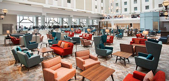 Atrium lounge with colourful armchairs beneath a tall glass-walled ceiling