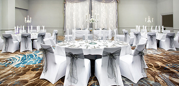 Wedding banquet room with round tables, white chair covers and candelabra centrepieces