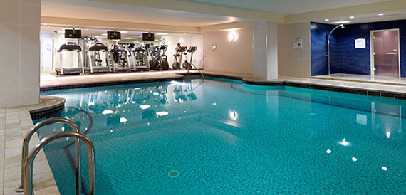 Indoor swimming pool alongside a gym with treadmills and exercise bikes