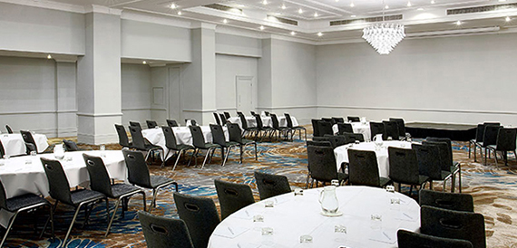 Function room set with round and rectangular tables beneath a crystal chandelier