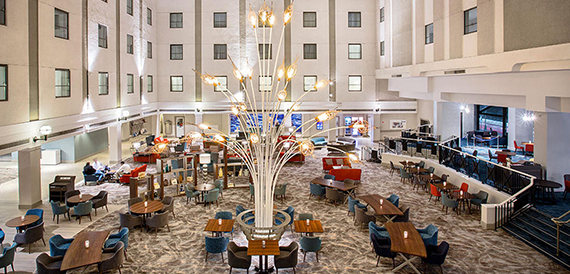 Hotel atrium lounge with a tall sculptural light fixture and colourful seating