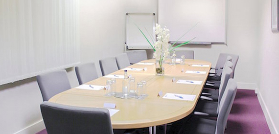 Oval boardroom table set with notepads facing a flip chart