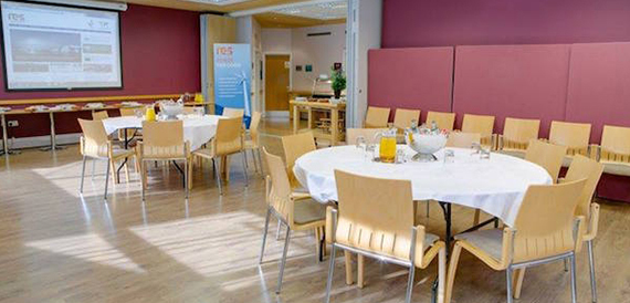 Breakout dining room with round tables facing a projector screen