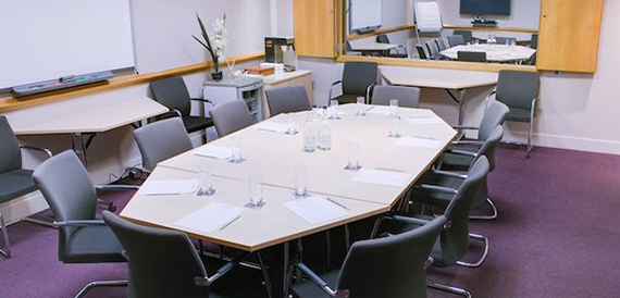 Hexagonal boardroom table set with notepads and dark upholstered chairs