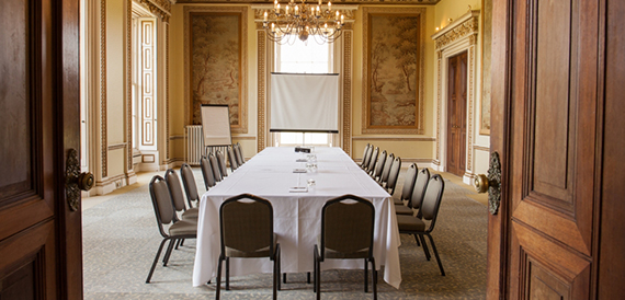 View through open doors into a boardroom with a long table and chandelier
