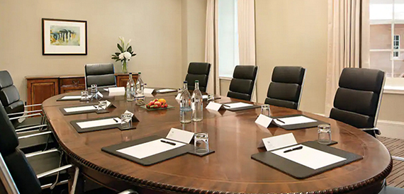Boardroom with a long table, dark leather chairs and fresh flowers