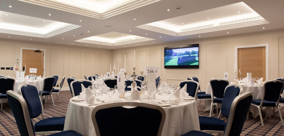 Round tables set formally with navy chairs for a dinner event