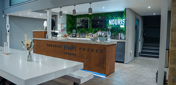 Cafe counter with a lit Nourish sign and staircase beyond