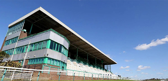 Brighton Racecourse's green and white grandstand against a clear sky