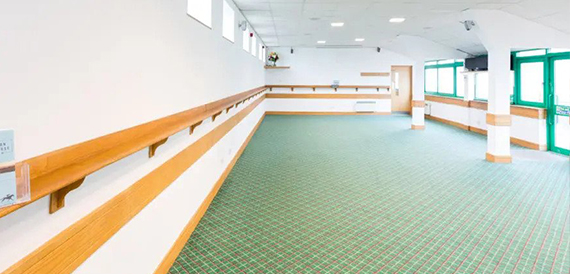 Empty room with green patterned carpet and a wooden handrail