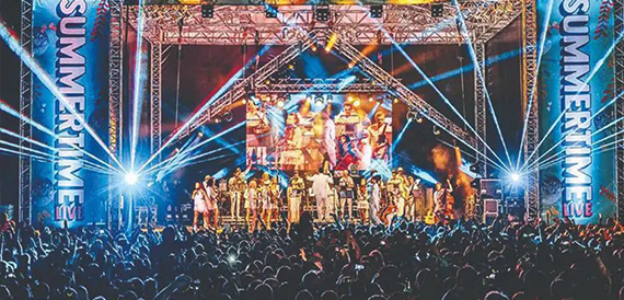 Concert stage with coloured lights and performers before a crowd