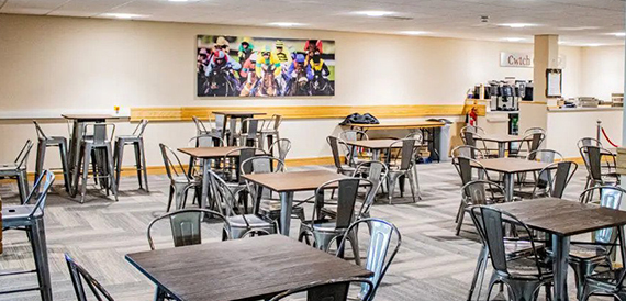 High tables and stools beneath a jockey mural in a casual dining space