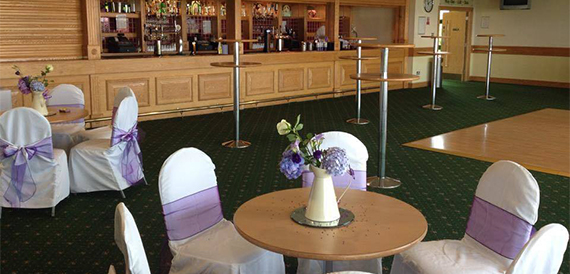 Bar area with a dance floor and lounge tables in white chair covers.